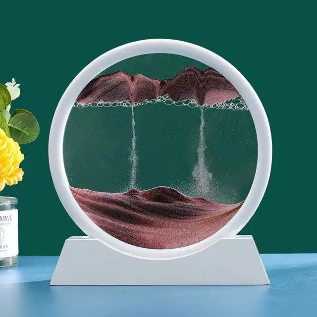 Circular sand sculpture with sand falling into a bowl on a blue surface with a green background